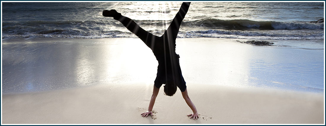 man standing on hands on beach